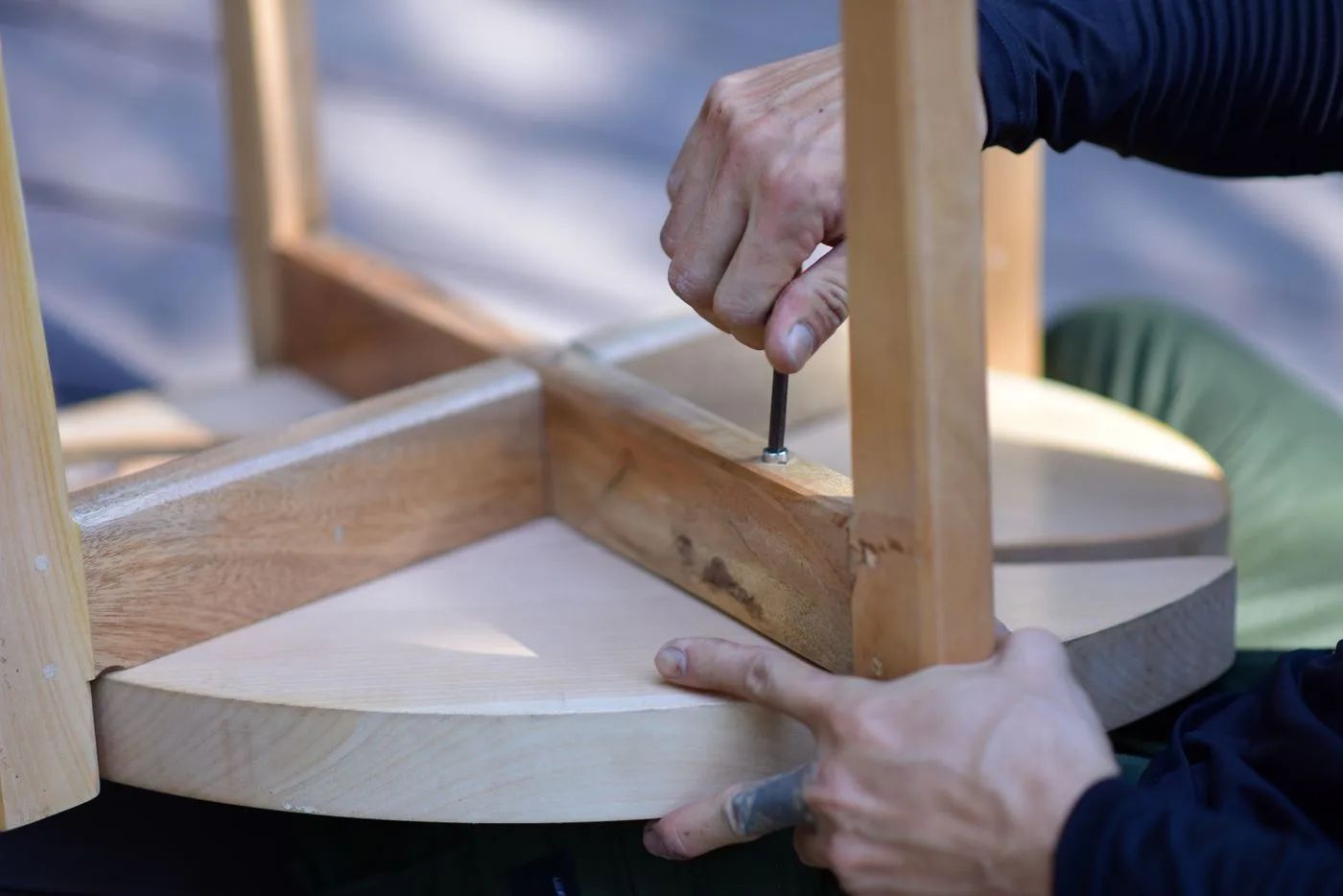 Manos montando un taburete de madera