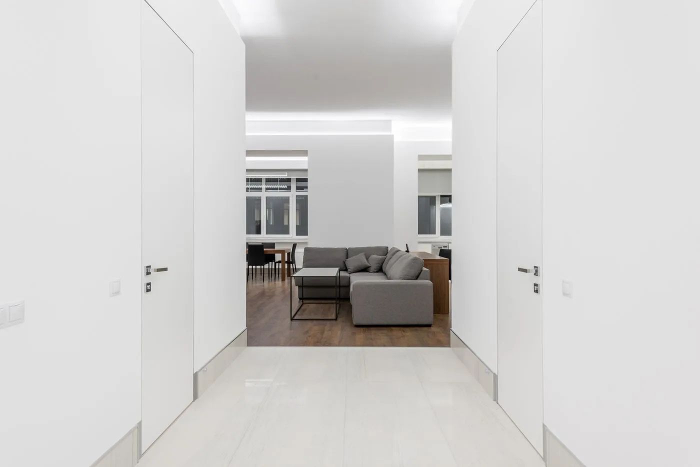 Pasillo y salón con paredes y puertas blancas
